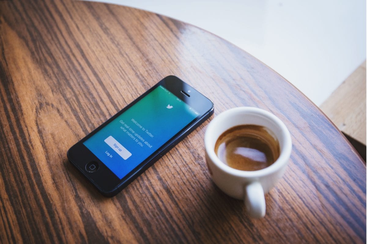 Phone displaying Twitter sign up screen lying on a café table